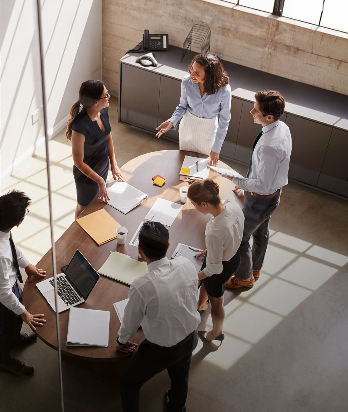 A team standing around a table in an office, working through a plan.